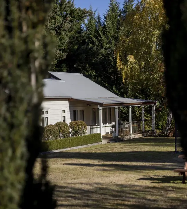 A house with a covered porch and a bench in the yard, showcasing Queenstown apartment accommodation.